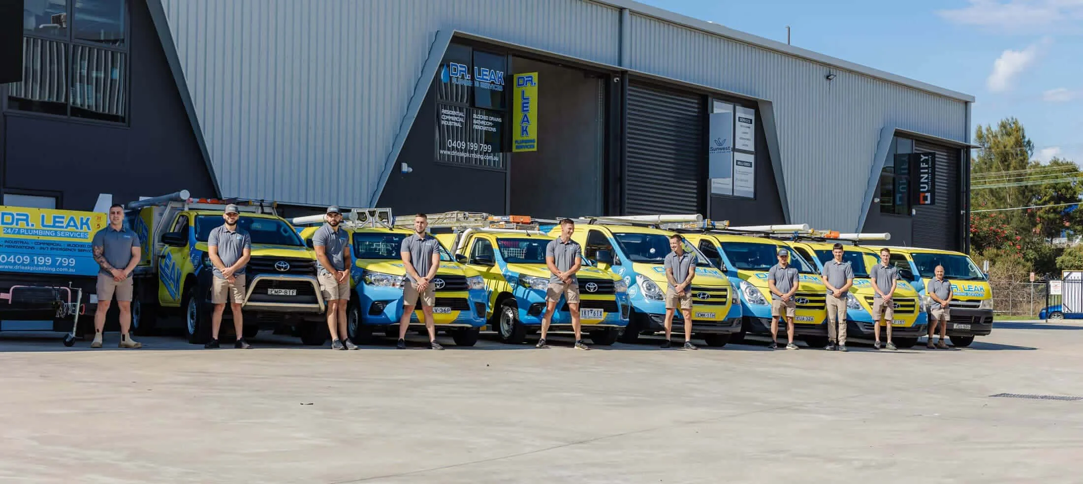 The Dr Leak Plumbing team standing with their service vehicles outside the company depot